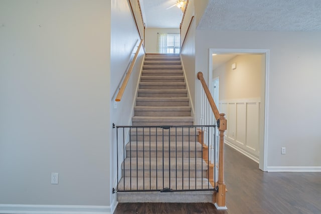 staircase with wood-type flooring and a textured ceiling