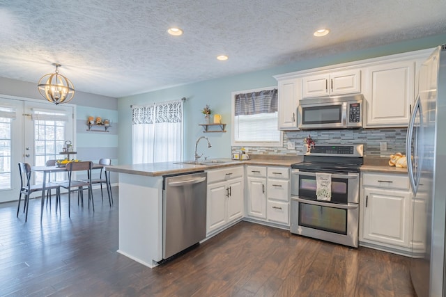 kitchen with white cabinets, stainless steel appliances, hanging light fixtures, and sink