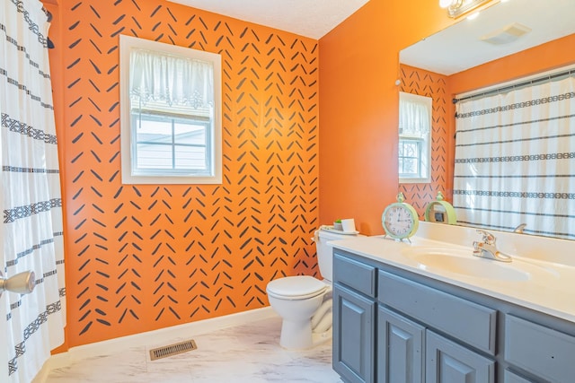 bathroom with a wealth of natural light, toilet, vanity, and a textured ceiling