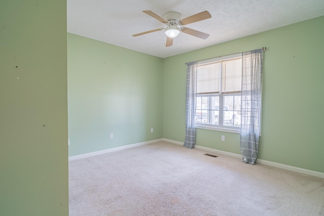 unfurnished room featuring ceiling fan, light colored carpet, and a textured ceiling