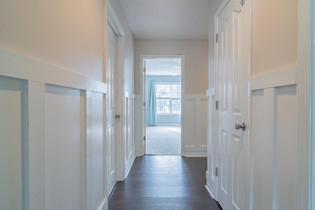 hall with a textured ceiling and dark hardwood / wood-style flooring