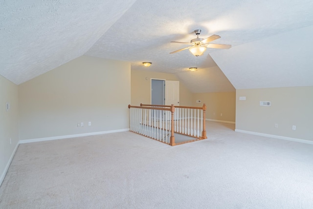 additional living space with light carpet, a textured ceiling, and lofted ceiling