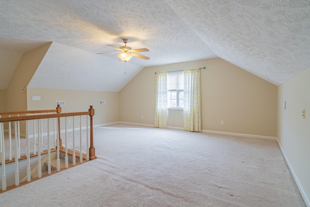 additional living space featuring light carpet, vaulted ceiling, ceiling fan, and a textured ceiling