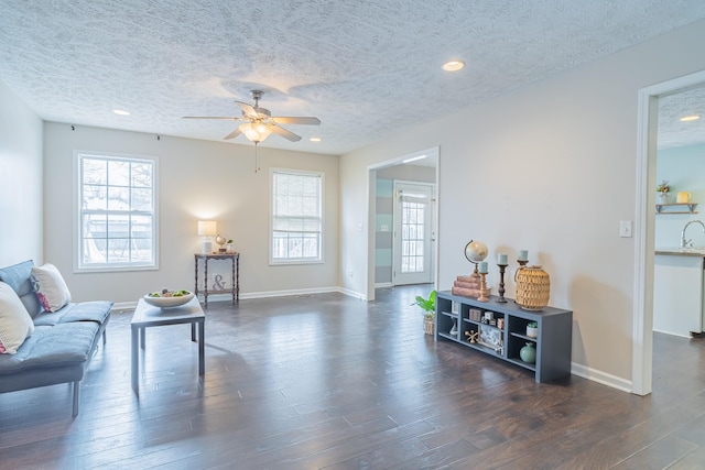 living room featuring ceiling fan, a textured ceiling, and dark hardwood / wood-style flooring