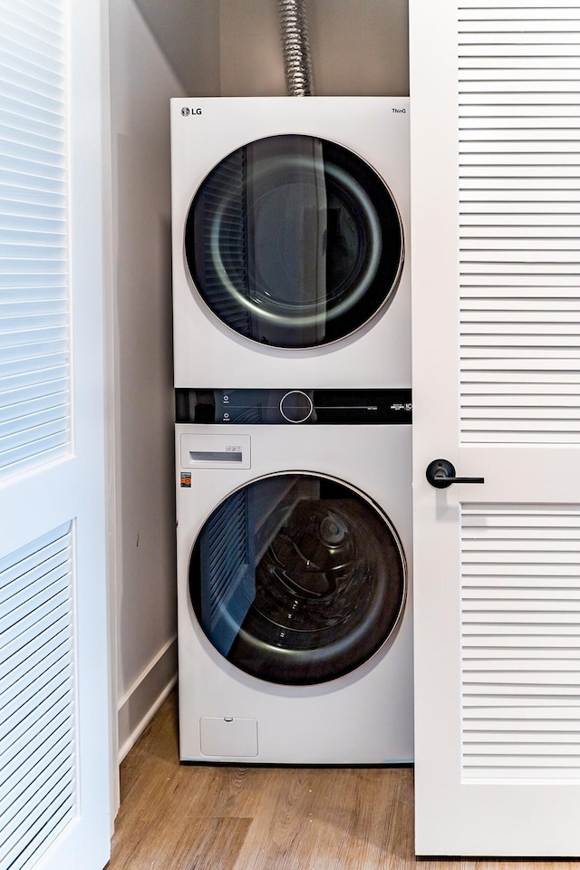 clothes washing area with stacked washer / drying machine and light hardwood / wood-style floors