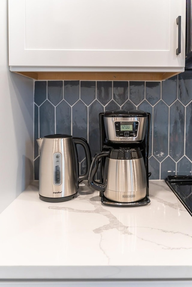 details featuring white cabinets, light stone countertops, and decorative backsplash