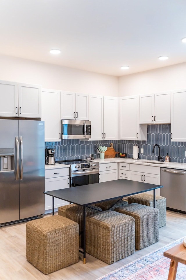 kitchen with stainless steel appliances, white cabinetry, and sink