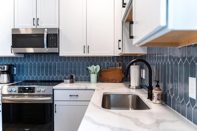 kitchen featuring appliances with stainless steel finishes, tasteful backsplash, white cabinetry, and sink