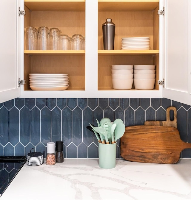 room details featuring white cabinets, decorative backsplash, and stovetop