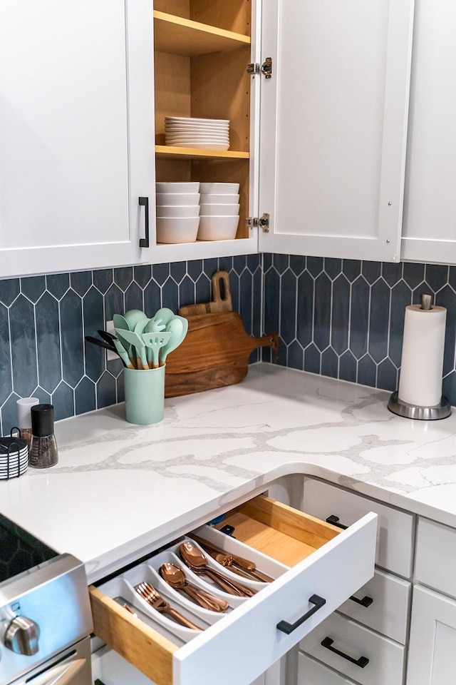 room details with white cabinets, light stone counters, and decorative backsplash