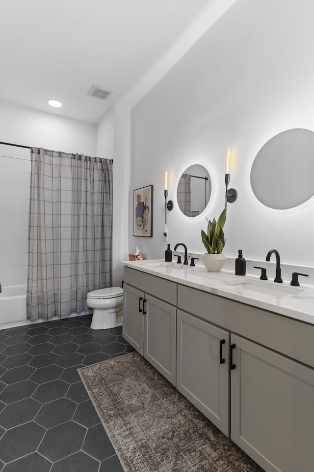 bathroom featuring double vanity, visible vents, toilet, and a sink