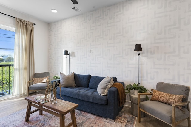 living room featuring visible vents, wood finished floors, and wallpapered walls