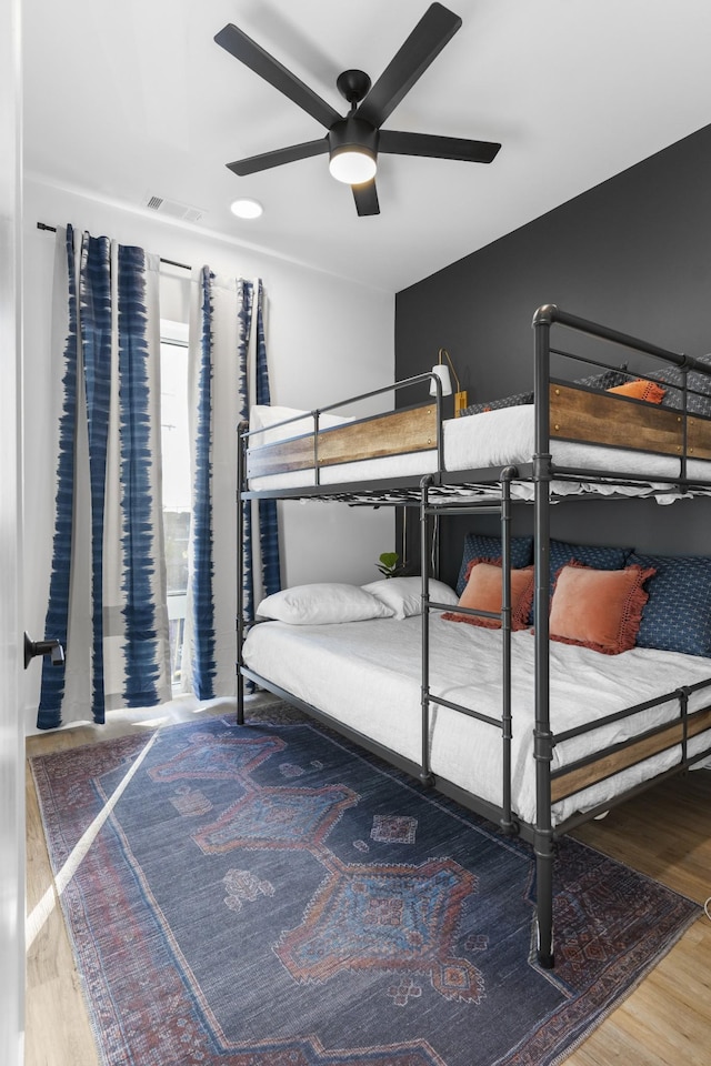 bedroom with a ceiling fan, wood finished floors, and visible vents