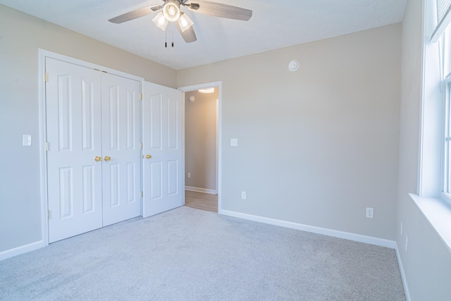 unfurnished bedroom with ceiling fan, a closet, and light carpet