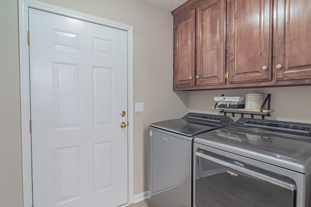 laundry area with a textured ceiling, cabinets, and washing machine and dryer