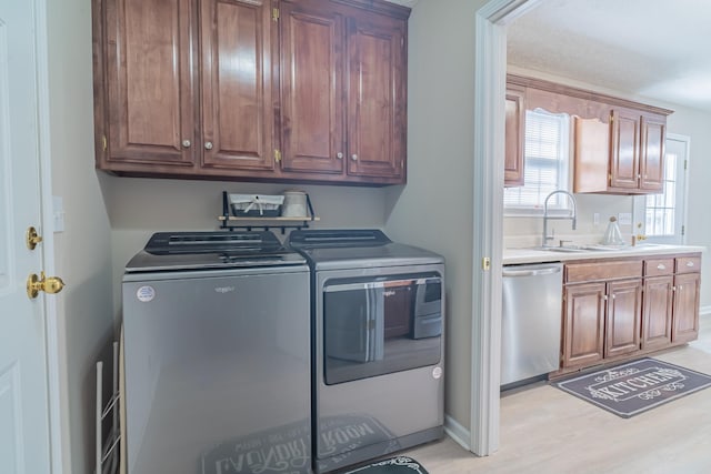 clothes washing area featuring separate washer and dryer, light hardwood / wood-style floors, cabinets, and sink