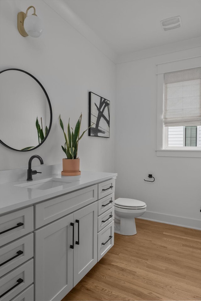 bathroom featuring toilet, vanity, and hardwood / wood-style floors