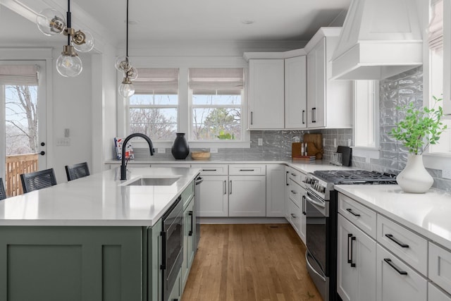 kitchen with gas stove, a center island with sink, white cabinetry, and premium range hood