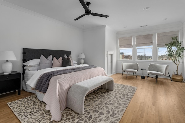 bedroom with ceiling fan, ornamental molding, and wood-type flooring