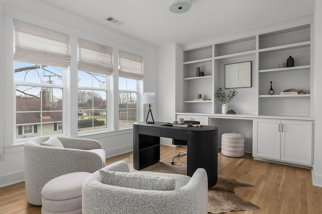 home office with light hardwood / wood-style floors and built in features