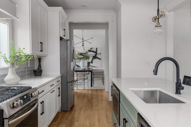 kitchen with decorative light fixtures, backsplash, white cabinets, appliances with stainless steel finishes, and sink