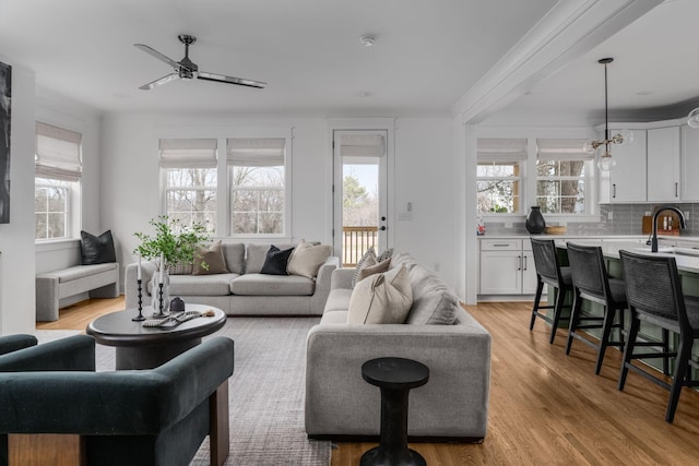 living room featuring sink, light wood-type flooring, ceiling fan, and ornamental molding