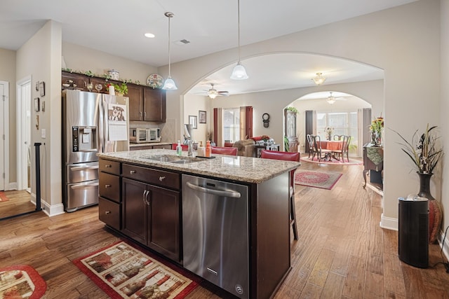 kitchen featuring sink, stainless steel appliances, an island with sink, ceiling fan, and dark brown cabinetry