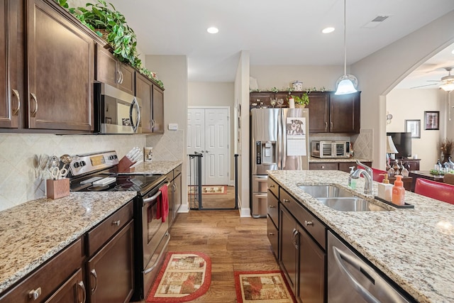 kitchen with hanging light fixtures, sink, appliances with stainless steel finishes, ceiling fan, and dark brown cabinetry