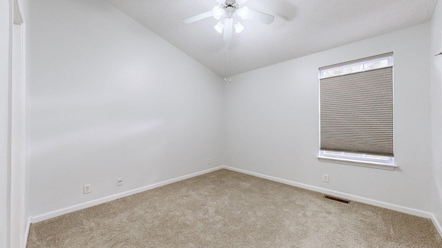 carpeted spare room featuring vaulted ceiling and ceiling fan