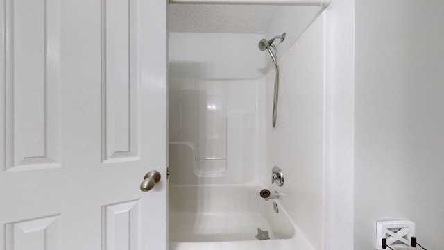 bathroom with a textured ceiling and shower / bathing tub combination