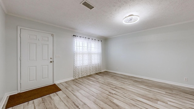 unfurnished room with ornamental molding, a textured ceiling, and light hardwood / wood-style floors