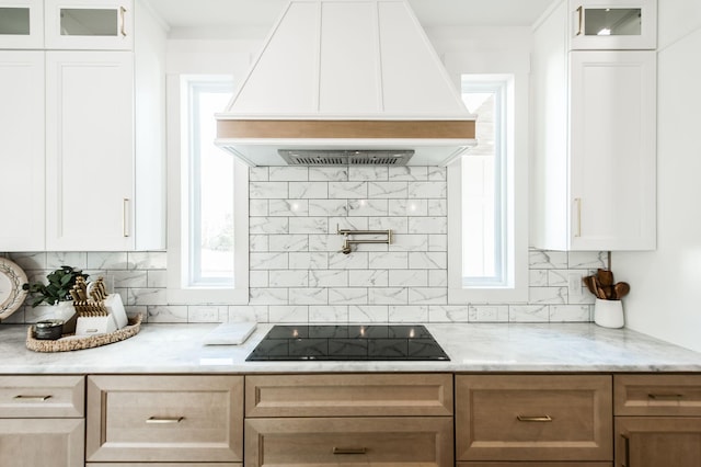 kitchen with white cabinetry, premium range hood, black electric cooktop, and decorative backsplash