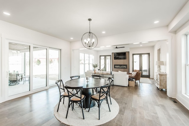 dining space with a chandelier, light wood-type flooring, and french doors