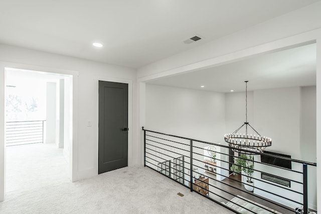 hallway with a notable chandelier and carpet floors