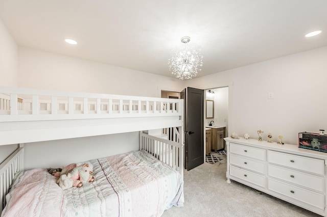 carpeted bedroom with connected bathroom, sink, and a notable chandelier