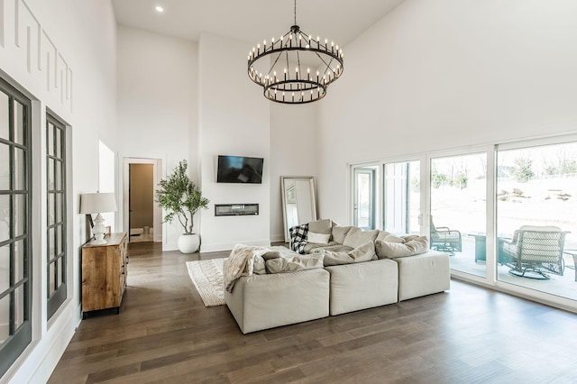 living room with a high ceiling, dark wood-type flooring, and an inviting chandelier