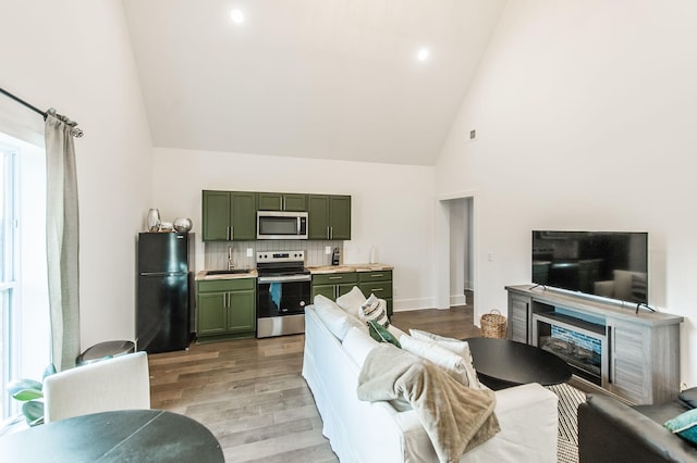 living room featuring sink, high vaulted ceiling, and light wood-type flooring