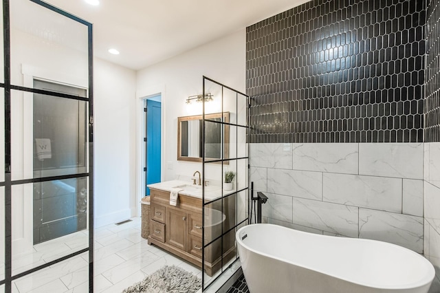 bathroom with vanity, a bathtub, and tile walls