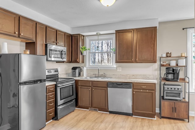 kitchen with stainless steel appliances, sink, and light hardwood / wood-style floors