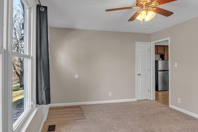 unfurnished room featuring ceiling fan, light colored carpet, and a wealth of natural light