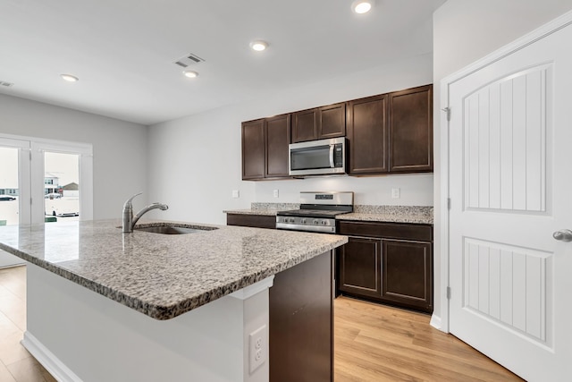 kitchen with sink, a center island with sink, dark brown cabinets, and appliances with stainless steel finishes