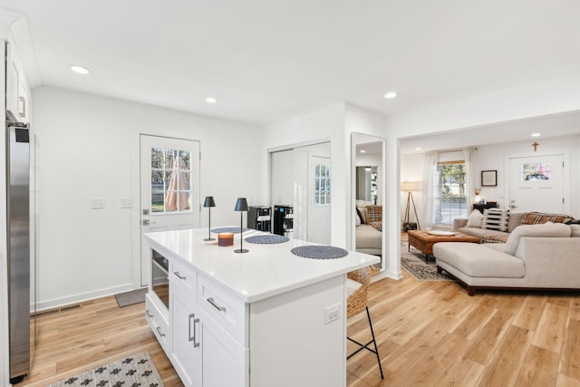 kitchen featuring a kitchen island, stainless steel fridge, a kitchen breakfast bar, and white cabinetry