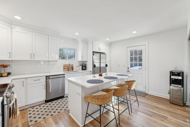 kitchen with sink, a kitchen island, white cabinets, and appliances with stainless steel finishes