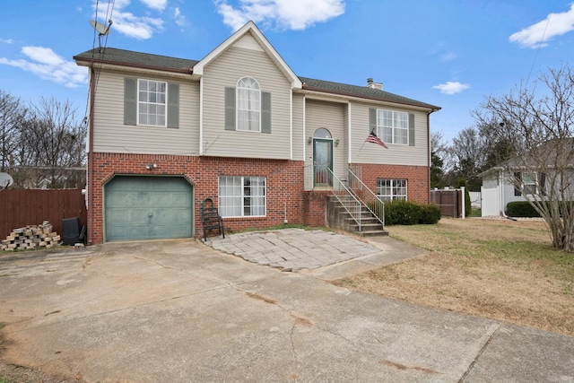 raised ranch featuring a garage, central AC unit, and a front yard