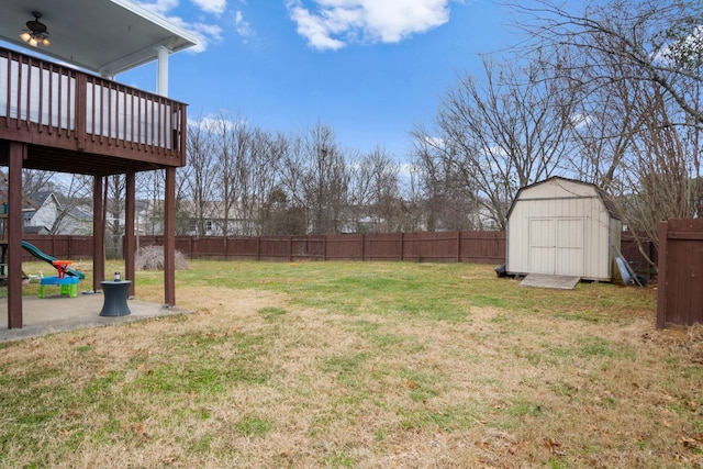 view of yard featuring a deck, a playground, and a shed