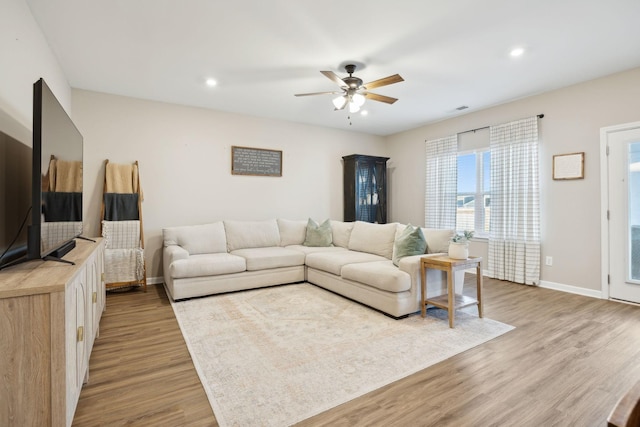 living room with ceiling fan and light hardwood / wood-style flooring