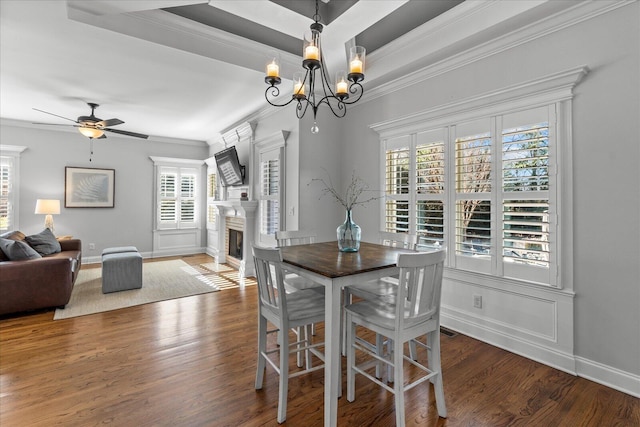 dining area featuring ceiling fan with notable chandelier, dark wood-type flooring, and crown molding