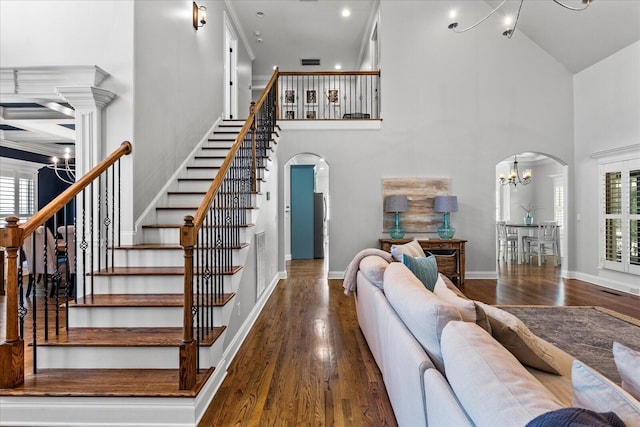 staircase featuring an inviting chandelier, high vaulted ceiling, and hardwood / wood-style floors