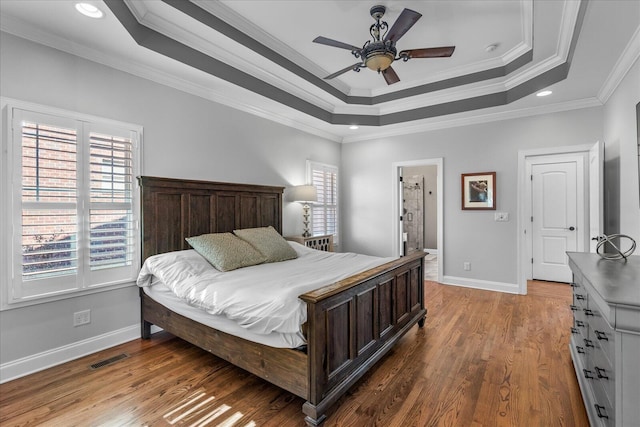 bedroom featuring ensuite bathroom, ceiling fan, a tray ceiling, and crown molding