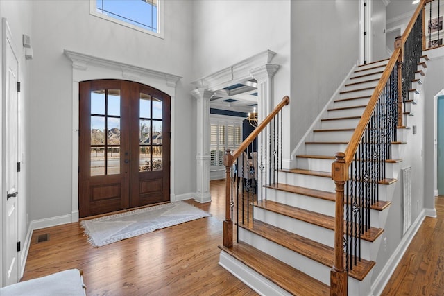 foyer entrance with ornate columns, french doors, dark hardwood / wood-style flooring, and a wealth of natural light